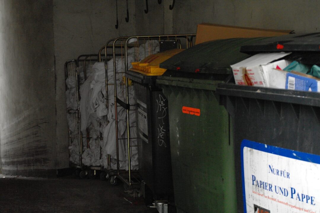 Müllcontainer für Papier und Pappe sowie Bioabfall und Kunststoffe hinter einem Supermarkt