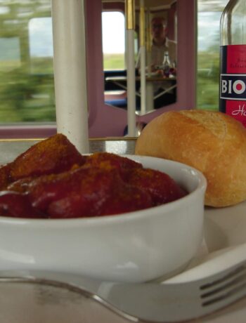 Currywurst mit einem Brötchen und Kaltgetränk im Bordbistro der Deutschen Bahn in einem Zug