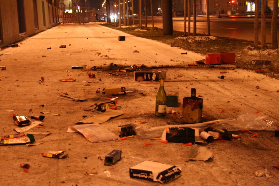 Bürgersteig voll mit Flaschen, abgebrannten Feuerwerkskörpern und sonstigem Müll in der Silvesternacht