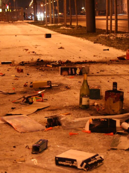 Bürgersteig voll mit Flaschen, abgebrannten Feuerwerkskörpern und sonstigem Müll in der Silvesternacht